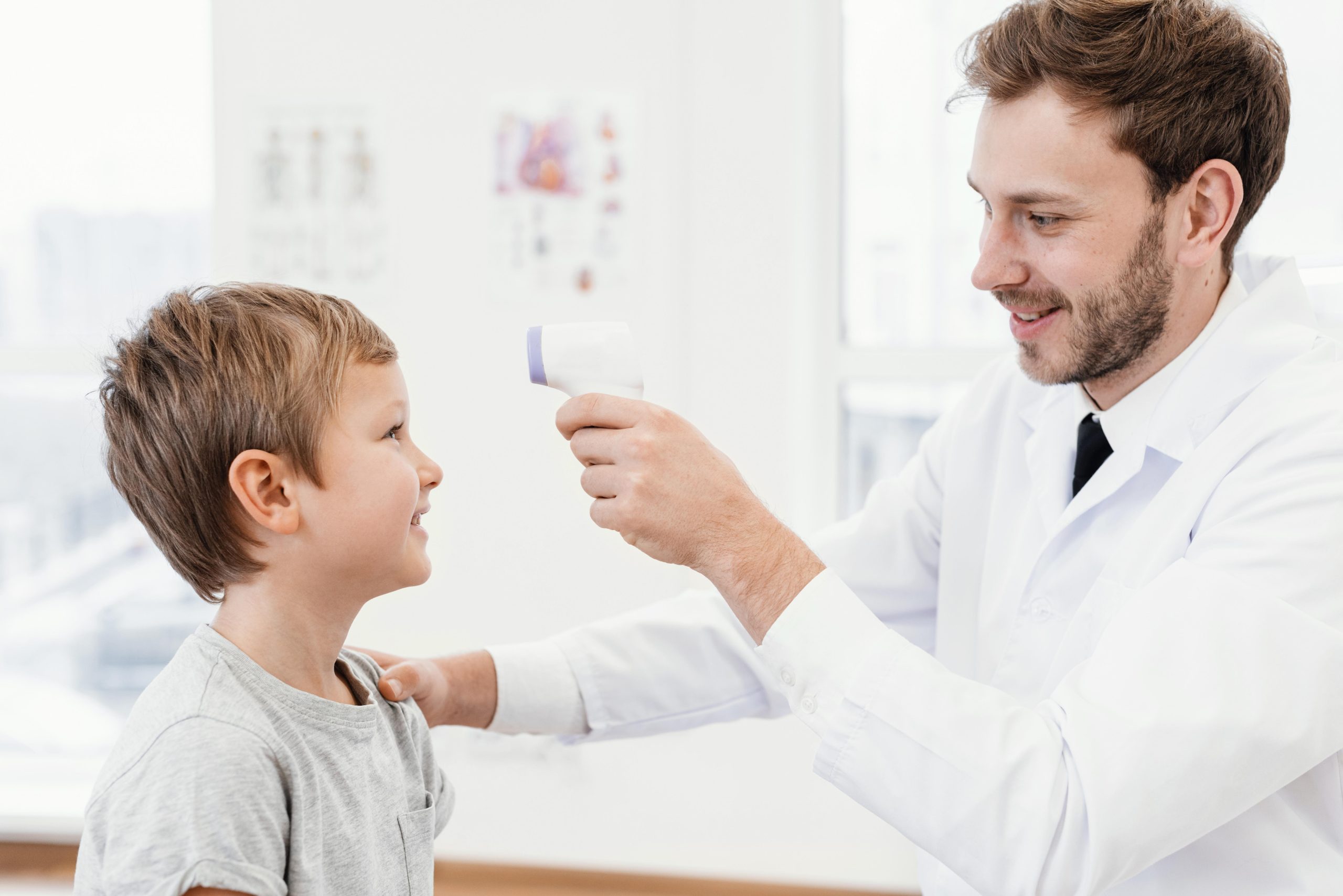 doctor taking small male child's temperature with a digital forehead thermometer