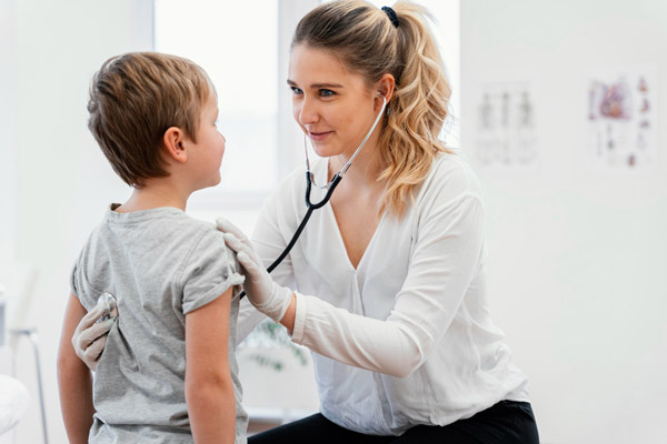 Doctor listens to child patients chest with stethoscope