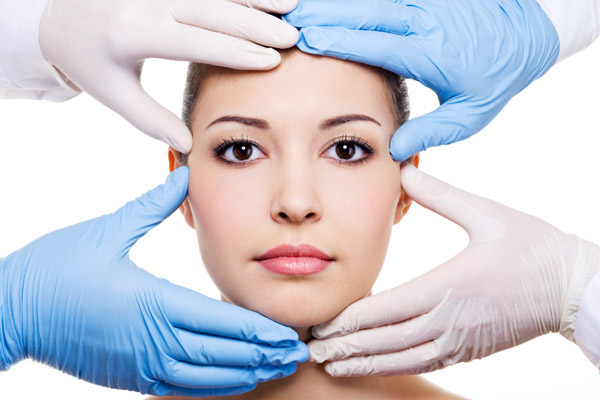 womans face with gloved hands examining