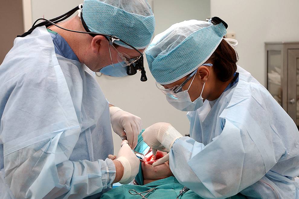 Surgeon and nurse removing tooth
